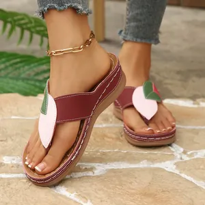 Gros plan de sandales compensées bordeaux pour femmes avec design en patchwork de feuilles