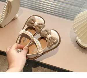 Vista detallada de zapatos Mary Jane beige para niños con lazo floral y tira de perlas