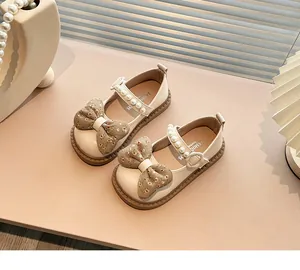 Vista detallada de zapatos Mary Jane para niña en crema con lazos y perlas.