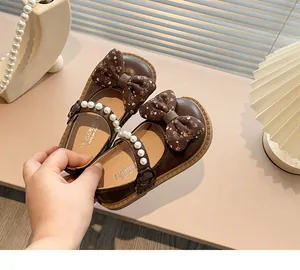 Primer plano de zapatos de princesa marrones para niña con lazos de flores y perlas