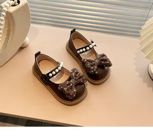 Detalle de zapatos Mary Jane marrones para niña con lazos florales y correas de perlas