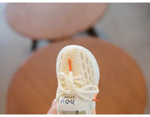 Macro detail of breathable beige knit mesh and orange lace tips on children's shoes