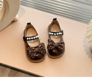 Primer plano de zapatos infantiles de cuero con lazo floral y perlas