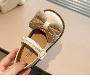 Primer plano de zapato Mary Jane blanco para niña con lazo floral y correa de perlas