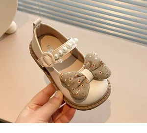 Detalle de zapato Mary Jane crema para niña con lazo floral y correa de perla