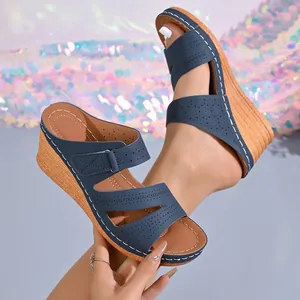Detalle de sandalias con cuña azul marino con diseño perforado y costuras blancas.