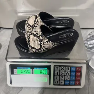 Primer plano que muestra el peso de 0,32 kg de las sandalias de cuña con serpiente para mujer