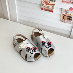 Nahaufnahme von silbernen Mädchen-Sandalen mit Cartoon-Design und weicher Sohle.