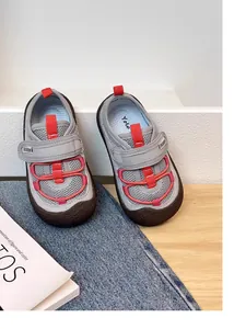 Close-up view of grey breathable mesh children's sneakers with red elastic accents