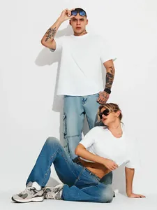 Paar trägt übergroße weiße T-Shirts in einem professionellen Modestudio-Setting