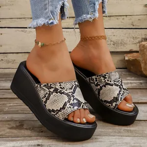 Primer plano de sandalias de cuña con plataforma para mujer con tira de elegante piel de serpiente.