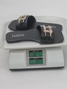 Macro view of black square-toe flat sandals with crystal chain on a digital scale