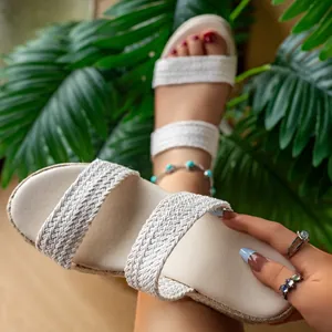 Gros plan sur les brides tressées beiges de ces sandales compensées d'été pour femmes.
