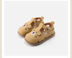 Detail van gele lederen peutersandalen met schattig berenontwerp en uitgesneden pootjes