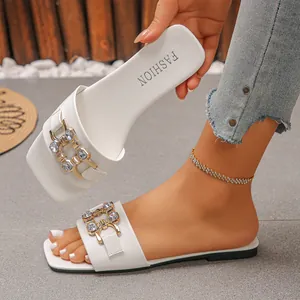 Detail view of elegant white square-toe flat sandals with luxury rhinestone chain buckle