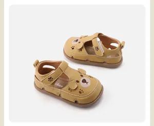 Gedetailleerd beeld van gele lederen peutersandalen met schattig berenontwerp