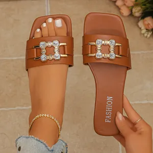 Close-up of brown flat sandals with rhinestone buckle and square toe design