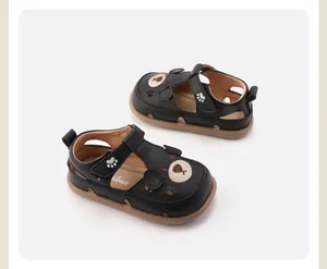Close-up van zwarte leren kindersandalen met schattig berenontwerp en een zachte zool