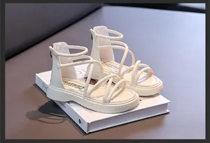 Dettaglio di sandali alla schiava color crema per bambina con cinturini e zip posteriore.