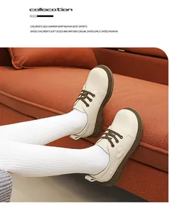Nahaufnahme cremefarbener Mädchen-Lederschuhe mit Herzmuster auf orangefarbenem Sofa