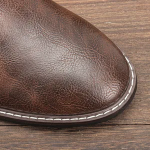 Dettaglio della punta in pelle marrone vintage di uno stivale con cuciture bianche e texture