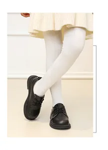 Detail der schwarzen Leder-Schnürschuhe für Mädchen mit weißen Strickstrumpfhosen