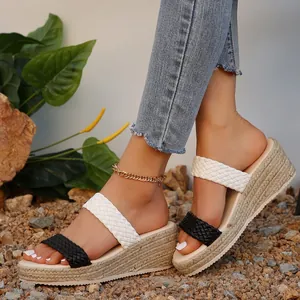 Sandales compensées d'été avec brides tressées noires et blanches portées dehors.