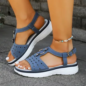 Close-up of blue platform sandals with laser-cut details and metallic ring buckle