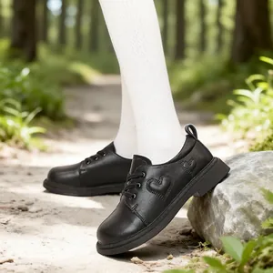 Preppy girls black leather shoes with heart detail shown in a forest path setting