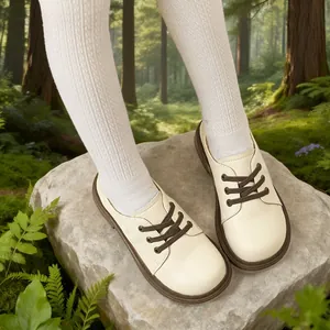 Academy style cream leather shoes for girls featuring brown laces on forest background