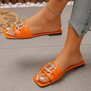 Detail view of orange flat sandals with sparkling rhinestone buckle and square toe