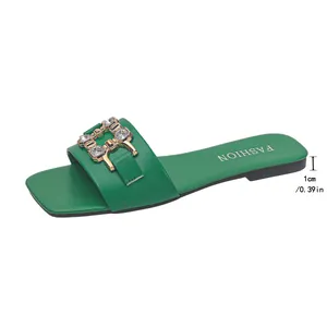 Close-up detail of green square-toe flat slide sandal with 1cm heel and crystal buckle.