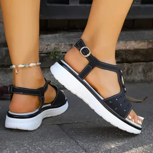 Detail view of black T-strap platform sandals with metal buckle and white wedge soles