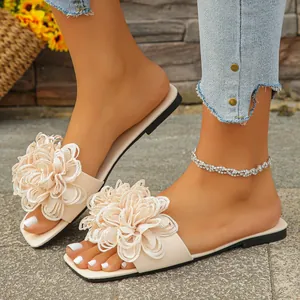 Macro detail of fashionable beige flat slippers featuring a large layered fabric flower decoration