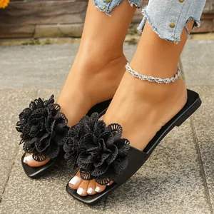 Close-up of black flat sandals featuring elegant large lace flower decoration