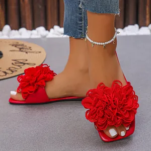 Detailed close-up of vibrant red flat sandals with oversized 3D fabric flower decoration