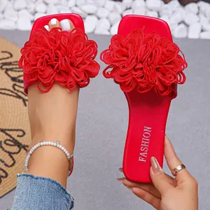 Close-up of stylish red flat slide sandals featuring large fabric flower decorations