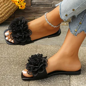 Detail view of black flat slide sandals with large 3D flower on feet for summer