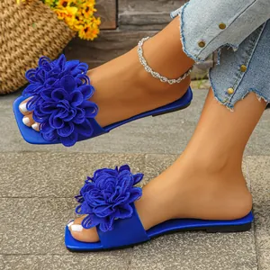 Detail of blue flat slides with large decorative fabric flowers for summer beach wear.