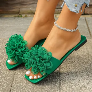 Detailed view of women's green flat slide sandals featuring large 3D woven flower decorations