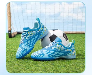 Detail view of light blue children's TF soccer shoes on artificial turf with a soccer ball.