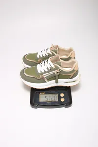 Medición que muestra el peso de un par de zapatillas de patchwork verdes de 572g en una báscula
