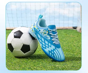 Detail view of blue children's turf soccer shoe leaning on a soccer ball