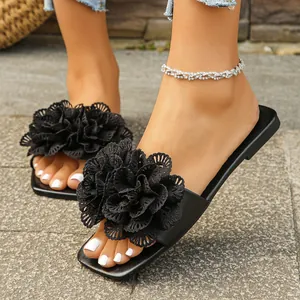 Close-up detail of women's black flat sandals with large decorative lace flowers.