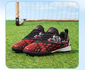Detail of red and black children's TF soccer shoes displayed on artificial turf.