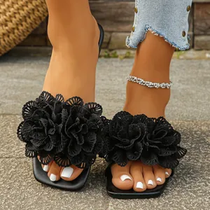 Detail of black flat slides with decorative 3D lace flowers on the strap