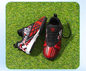 Close-up view of red and black children's TF soccer shoes featuring geometric patterns on green turf