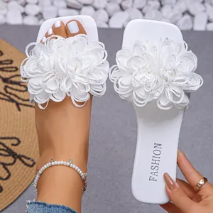 Detailed close-up of white women's flat slippers with large decorative fabric flowers.