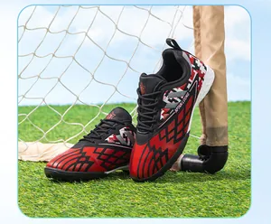 Side view of red and black kids TF soccer shoes on artificial turf for kids training