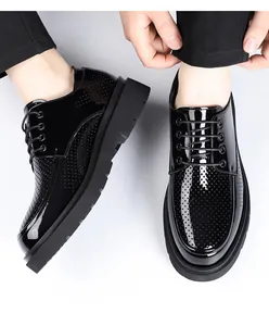 Close-up van zwarte geperforeerde derby schoenen met glanzende afwerking en dikke zool.